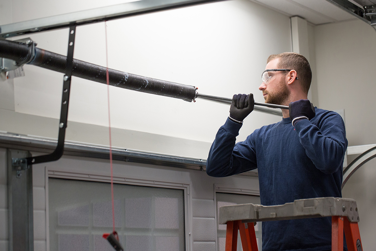 Technician servicing a garage door spring assembly