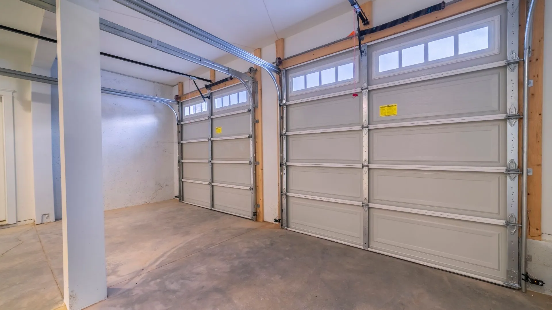 A clean residential garage with two installed garage doors