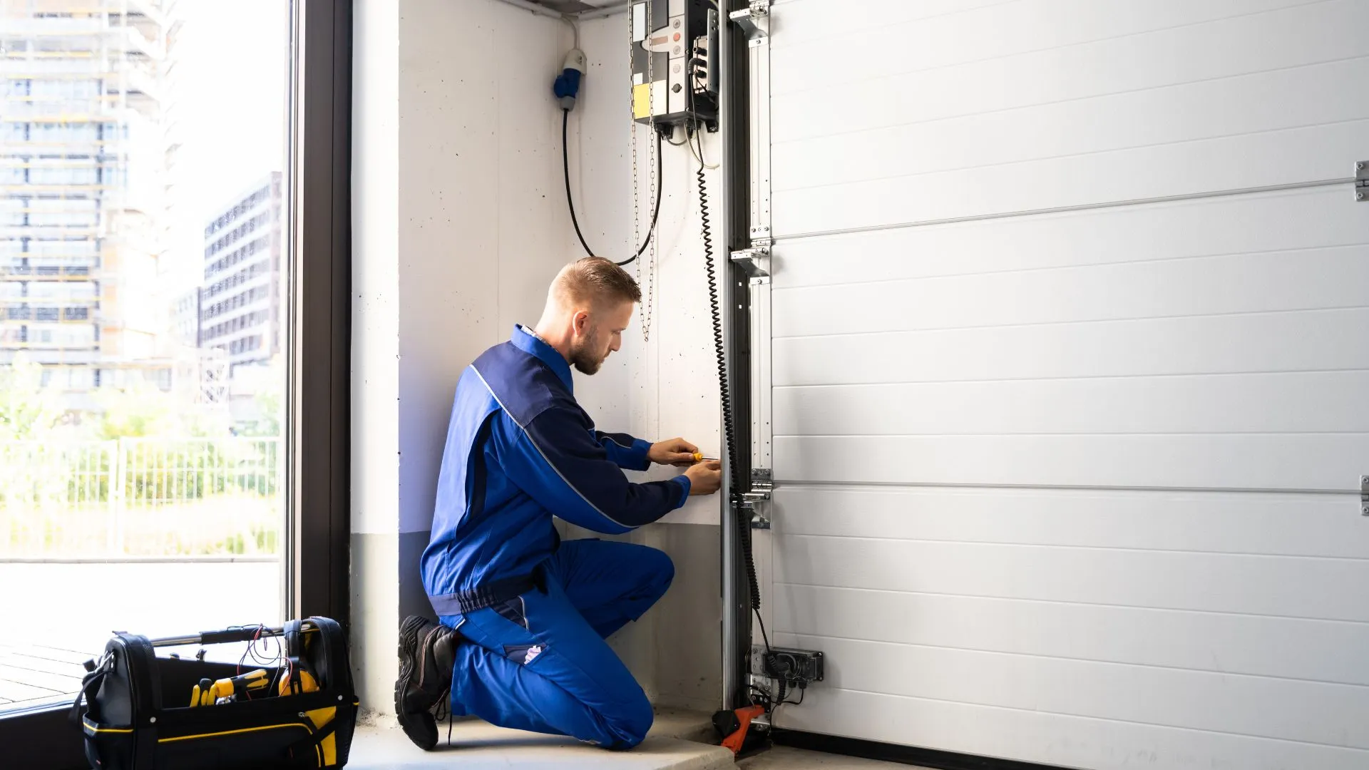 Garage door technician working beside a sectional door